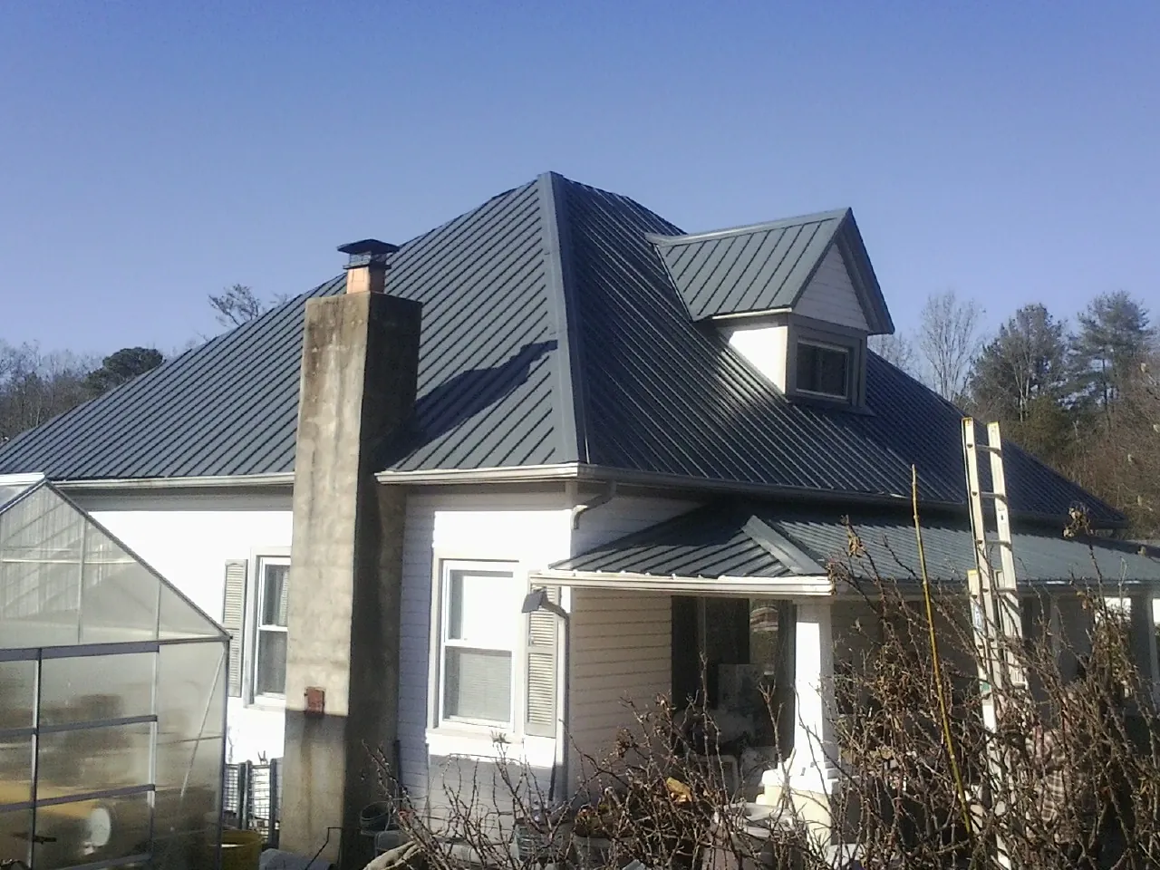 Dark blue standing seam metal roof on a white farmhouse with dormer — Slate & Tile Roof Repair by Roofing Brothers in Chino Valley