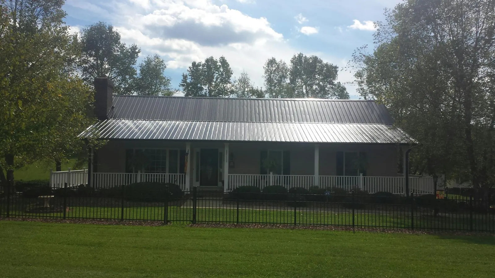 Gray metal roof on a brick ranch with a full width front porch — Gutter Guard Installation work by our crew in Chino Valley