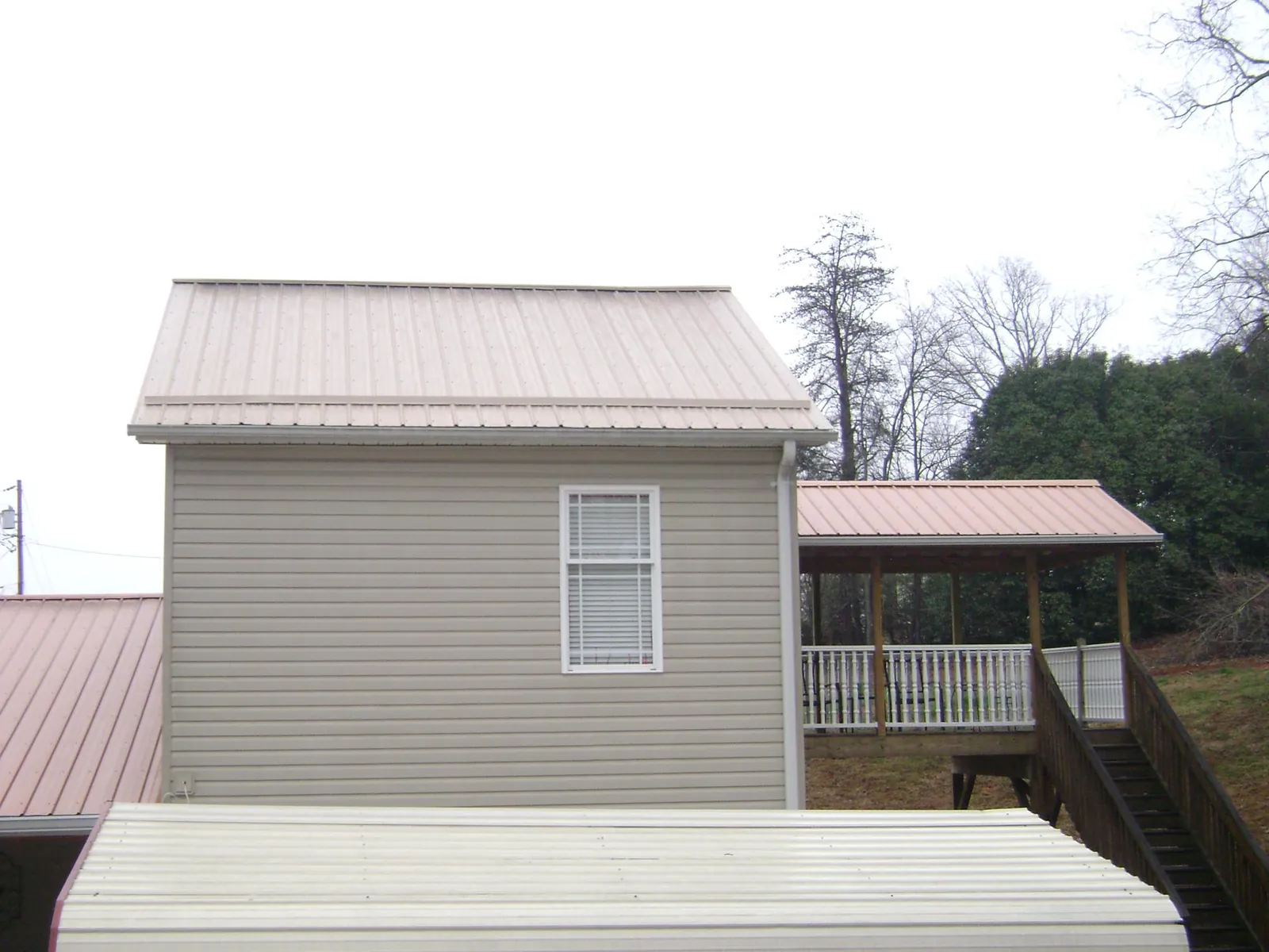 Tan metal roofs on a two story addition and attached porch, from a Roof Replacement job in Chino Valley