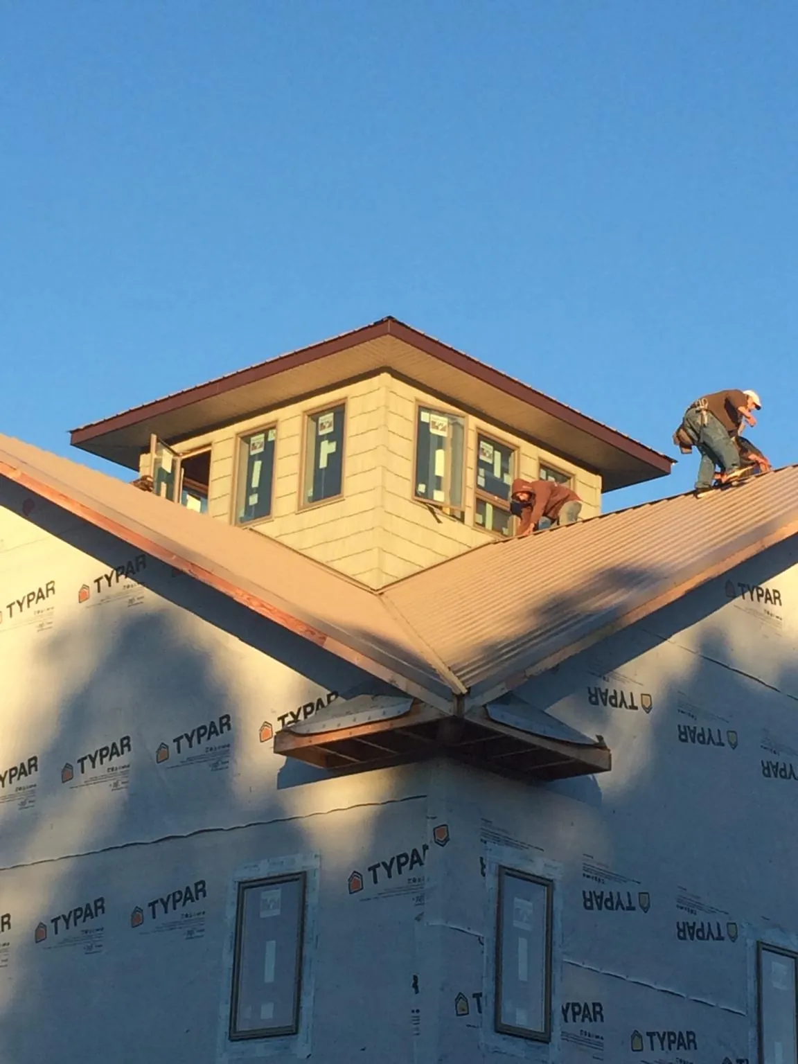 Roofers working around a rooftop cupola on a new metal roof at sunset — Roof Waterproofing in Chino Valley by Roofing Brothers